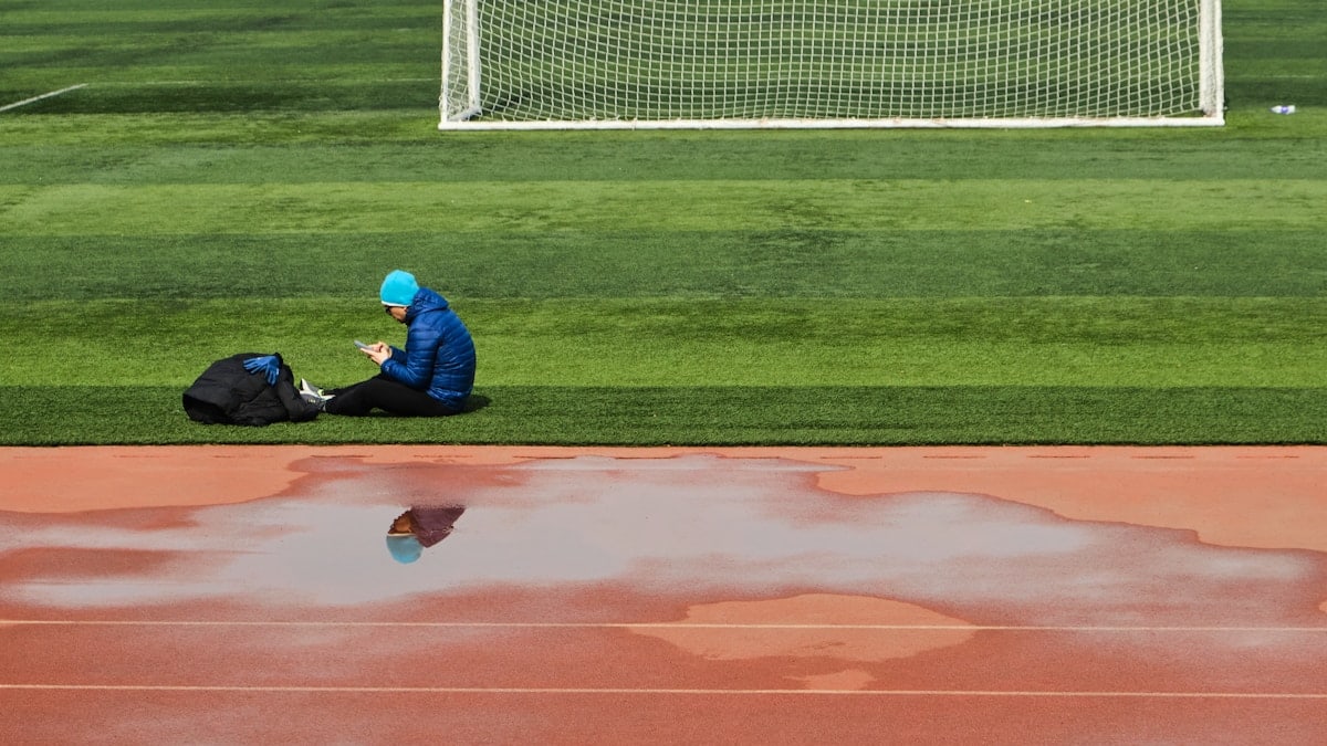 man in blue jacket and blue denim jeans sitting on green grass field during daytime